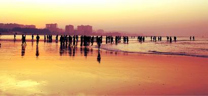 landscape of the crowd on a sand beach at the sunset