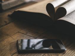 heart shaped book pages are reflected on the phone screen