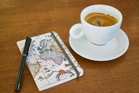 notebook with pen and cup of coffee on the table