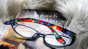 glasses and a book lie on a fluffy carpet