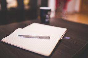 Notebook, Paper and pen on a table in a blurred background
