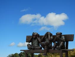 Three wise monkeys on bench, contemporary sculpture outdoor