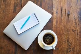 notebook with pen on tablet and a cup of coffee on the table