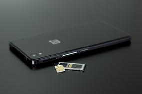 black smartphone and sim card on black surface