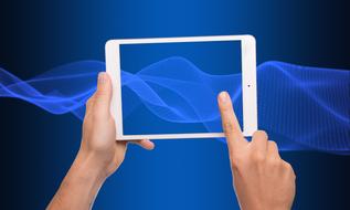 Tablet Computer in hands at abstract blue background