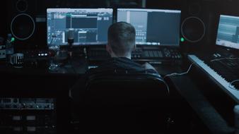 young man behind monitors in a recording studio