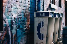 pay phones on an old dirty brick wall