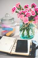 smartphone on the notepad near the beautiful pink and white flowers