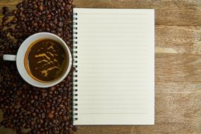 cup of coffee beans and blank notepad