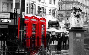 monochrome photo of a red telephone booths on a street in London, England