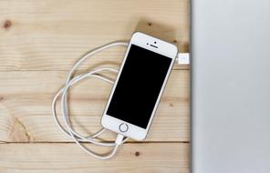 white smartphone with cable on wooden table