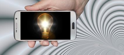 shining vintage light bulb on screen of smartphone