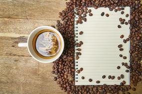 cup of coffee and white sheet on coffee beans