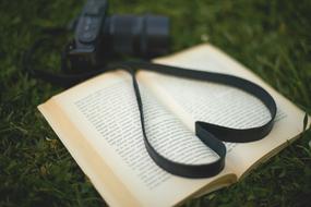 Photo camera strap in heart shape on open book