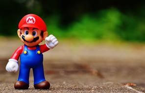 Cute and colorful figure of the Mario, in red and white cap, near the colorful plants