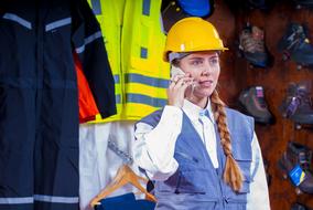 cheerful caucasian girl in Helmet in front of Industrial safety clothing