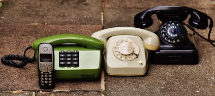 Shiny, green, white and black retro phones, on the ground