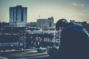 Guy in cap, texting on the phone, on the bridge, among the beautiful and colorful buildings