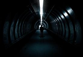 Silhouette of a person in the dark tunnel with lights