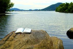 pencil, open notepad on stone by the lake