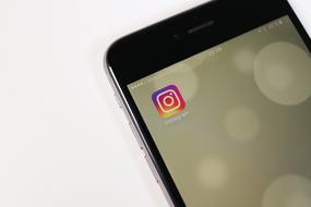 Colorful "Instagram" app icon on the screen of the black smartphone