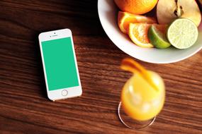 sliced fruits in a bowl, freshly squeezed juice and a smartphone on the table