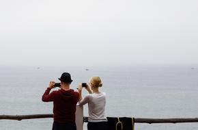 tourists with cameras on the coast on a cloudy day