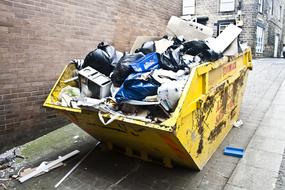 Trash in container at brick wall