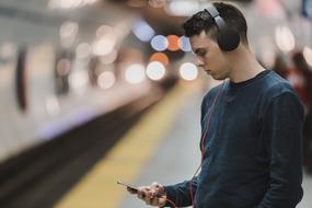 young man with smartphone and headphones in the subway