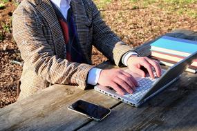 man typing on laptop computer outdoor