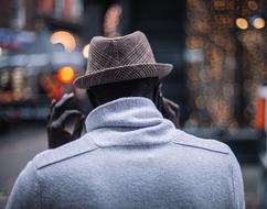Back view of a man, in the hat, among the city, with the colorful lights