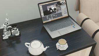 Laptop and tea set on table