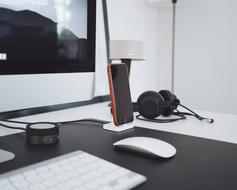 Close-up of the desk, with the Apple computer, mouse, keyboard, smartphone and headphones