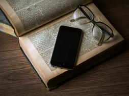 glasses and a smartphone lie on an open book