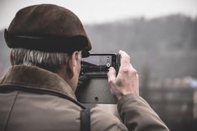 senior man taking photo of landscape with smartphone at winter