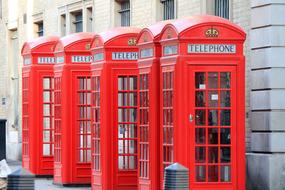 red telephone booths in a row on the streets of london