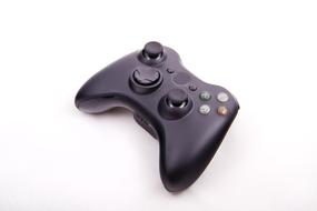 Shiny, black game joystick with colorful buttons, on the white surface