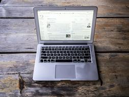 Top view of the beautiful, grey Mackbook with black buttons, on the wooden surface