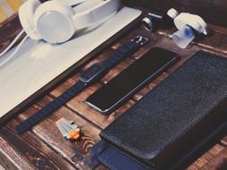 gadgets and wrist watch on wooden desk