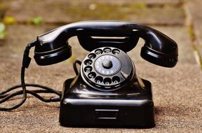 black retro telephone stands on a paved path