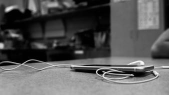 black and white photo of headphones near laptop