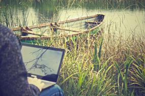 girl working on laptop by the lake