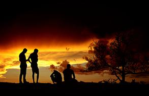 Friends, four men silhouettes at sunset sky