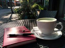 pen on closed notebook and green drink in cup on table outdoor