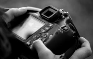 camera in hands in black and white background close up