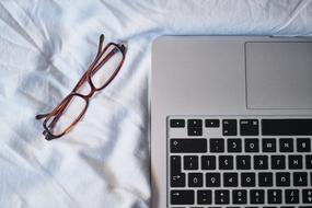 glasses near the laptop on the bed