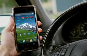 Beautiful landscape with the green hill and snowy mountain, on the smartphone screen, in the person's hand in the car