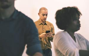 man with smartphone behind people