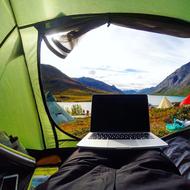 Using laptop, in the tent, outdoors, among the beautiful mountains