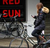 girl with a mobile phone on a bicycle on a city street